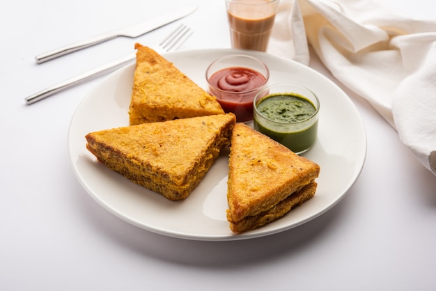 Sandwich Bread Pakora lub pakoda w kształcie trójkąta podawana z ketchupem pomidorowym, zielonym chutneyem, popularną indyjską przekąską na herbatę