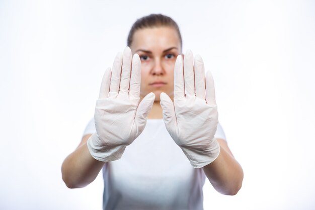 Zdjęcie sanitariusz dziewczyna zakłada białe rękawiczki medyczne na ręce. ochrona przed zarazkami i wirusami. jest w białej koszulce na białym tle.