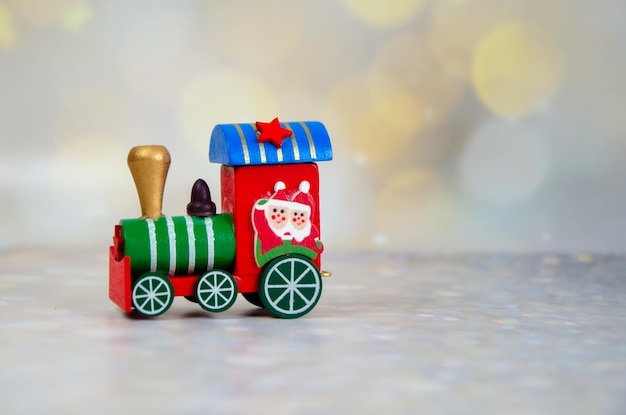 Santa Claus czerwony zabawka pociąg na tle złotego bokeh. Selektywne skupienie. Świąteczna kartka z życzeniami
