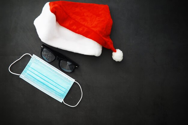 Santa Claus kapelusz, okulary i nos z maską na czerwonym tle. Koncepcja obchody Bożego Narodzenia lub nowego roku. Świąteczny renifer wykonany z maski ochronnej i ozdób. Pojęcie opieki zdrowotnej.