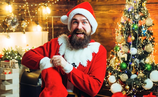 Santa hipster z bożonarodzeniowymi pończochami mężczyzna pozuje na boże narodzenie drewniane tła zimowe emocje