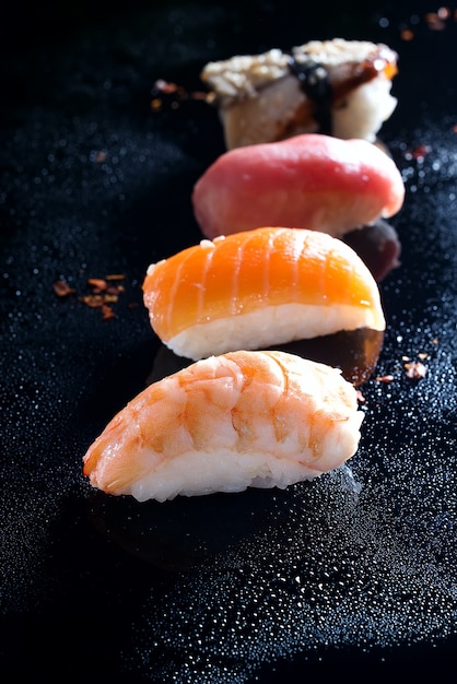 Sashimi, uramaki i nigiri z ryżem, łososiem lub tuńczykiem, krewetki w kolorze czarnym z kroplami wody