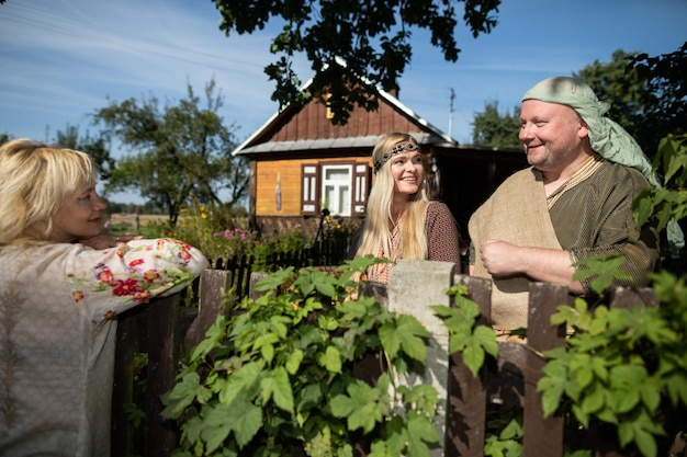 Zdjęcie sąsiedzi rozmawiają z uśmiechem na twarzach, stojąc przy starym drewnianym ogrodzeniu