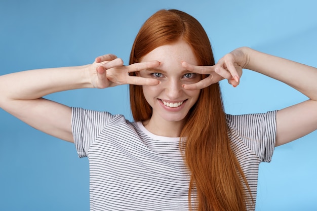 Zdjęcie sassy, buntownicza, zmysłowa, przystojna ruda dziewczyna niebieskie oczy uśmiechnięte bezczelnie okazywać znaki pokoju zwycięstwo uśmiechnięte oczy zadowolona pewna siebie ekspresja pewna siebie pozytywna postawa, tło studyjne.