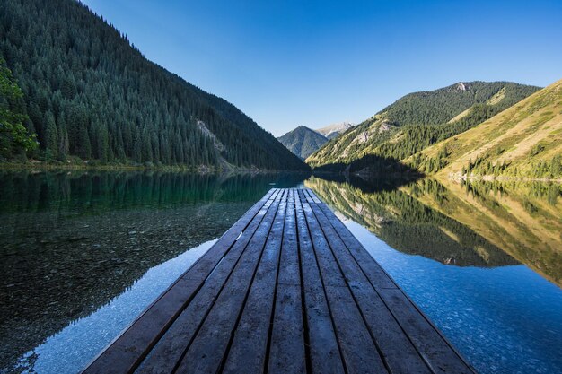 scena leśna i drewniane molo na górskim jeziorze Kolsai Lake w Kazachstanie