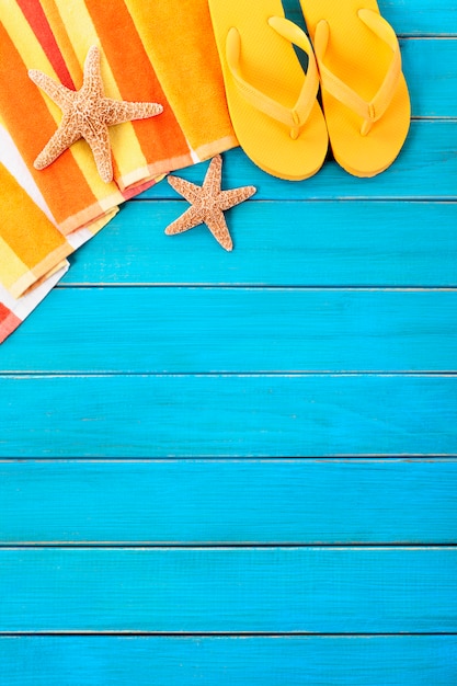 Scena plażowa z pomarańczowymi ręcznikami w paski, rozgwiazdy i klapki