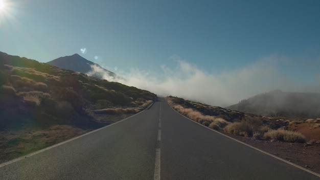 Scena z góralską drogą w jasnym słońcu i chmurach żeglowania. Malowniczy krajobraz Teneryfy, Park Narodowy Teide