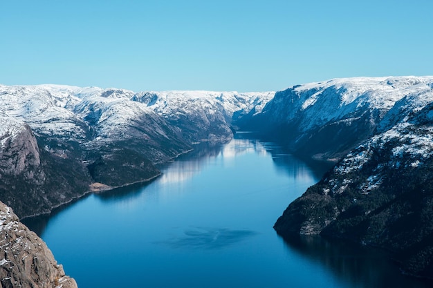 Sceniczny krajobraz jeziora z skalistym brzegiem z górami z śnieżnymi szczytami Górny widok na Pulpit Rock Preikestolen Lysefjord Norwegia