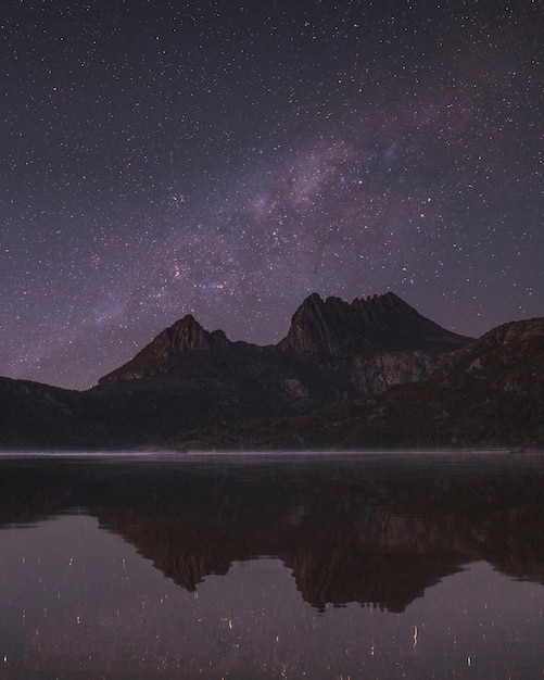 Zdjęcie sceniczny widok góry przy jeziorze na tle nocnego nieba