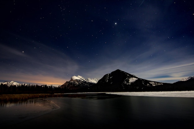 Sceniczny widok jeziora i skalistych gór na tle nocnego nieba