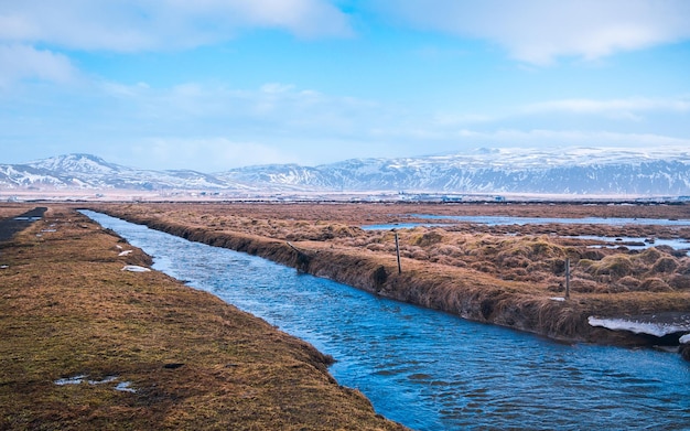 Sceniczny widok na rzekę przez pokryte śniegiem góry na tle nieba