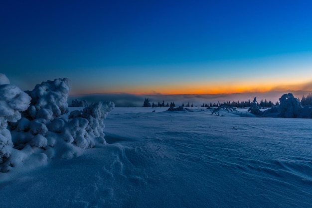 Sceniczny widok pokrytego śniegiem pola na tle nieba podczas zachodu słońca
