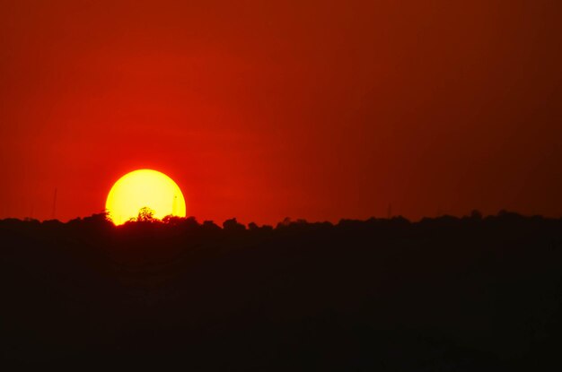 Zdjęcie sceniczny widok pola sylwetki na pomarańczowym niebie