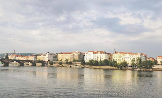 Sceniczny widok rzeki przez budynki w mieście na chmurnym niebie.