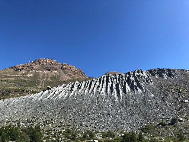 Sceniczny widok skalistych gór na tle jasnego niebieskiego nieba