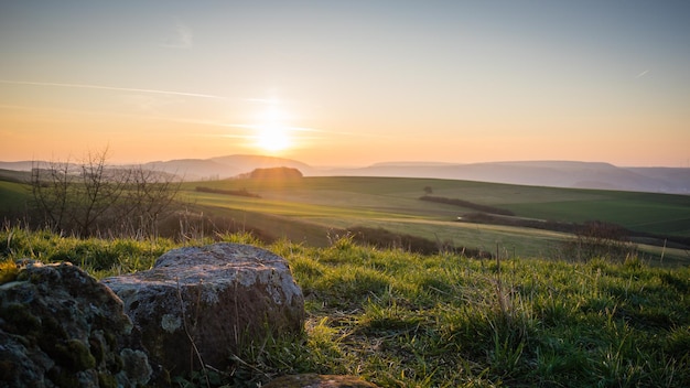 Sceniczny widok trawiastego krajobrazu na tle nieba podczas wschodu słońca