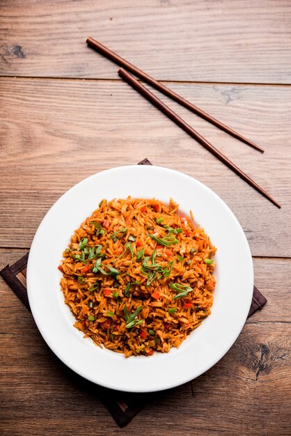 Schezwan Fried Rice Masala to popularne indochińskie jedzenie podawane na talerzu lub misce z pałeczkami