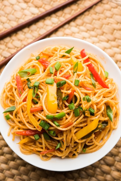 Schezwan Noodles lub warzywny Hakka Noodles lub chow mein to popularne przepisy indochińskie, podawane w misce lub talerzu z drewnianymi pałeczkami
