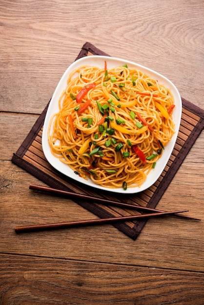 Schezwan Noodles lub warzywny Hakka Noodles lub chow mein to popularne przepisy indochińskie, podawane w misce lub talerzu z drewnianymi pałeczkami