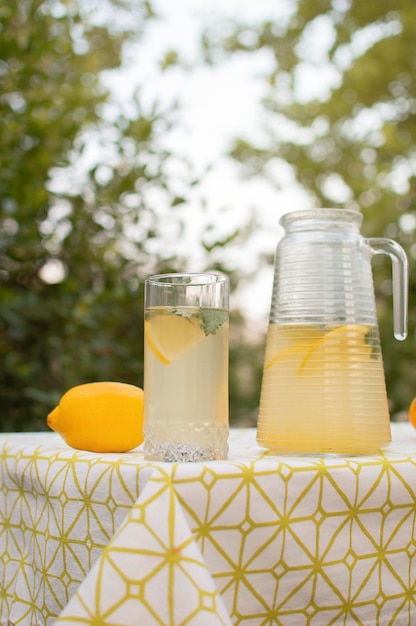 Schłodzona świeżo przygotowana lemoniada i owoce na stole na zewnątrz Letni napój orzeźwiający Przygotowanie napoju lemoniadowego Fotografia pionowa