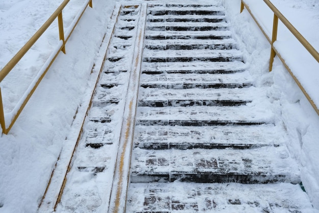 Schody na ulicy pod śniegiem. Traumatyczne miejsce śliskich stopni do zejścia i wejścia.