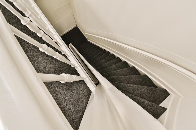 Zdjęcie schody z czarnym i białym dywanem na dole prowadzące na drugie piętro w budynku mieszkalnym
