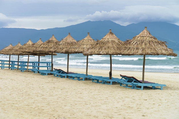 Schroniska dla palm i leżaki na plaży China Beach w Da Nang w Wietnamie. Nazywana jest również plażą Non Nuoc. Morze Południowochińskie i Góry Marmurowe w tle.