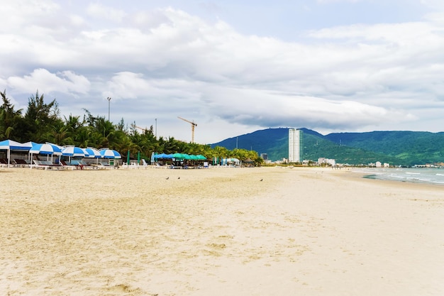 Schroniska dla palm i ludzie na China Beach w Danang w Wietnamie. Nazywana jest również plażą Non Nuoc. Morze Południowochińskie i Góry Marmurowe w tle.