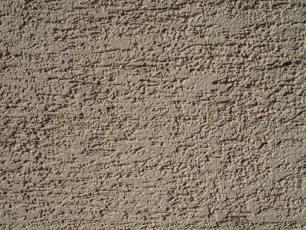 Ściana domu z własnoręcznie wykonaną elewacją otynkowaną Na ścianę nakładana jest zaprawa cementowa rozmazana szpachelką Na tynk błyskawicznie nałożono dekoracyjny wzór