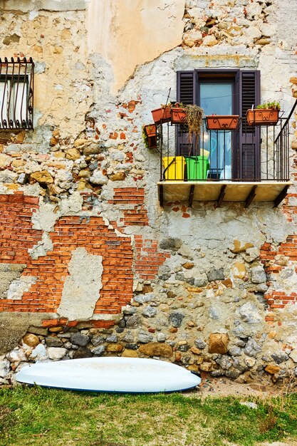 Ściana starego budynku nad morzem i małą łódką w Cefalu, Sycylia, Włochy