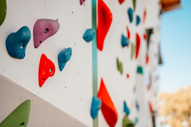 Ściana z chwytami wspinaczkowymi w siłowni Ćwiczenie wspinaczki na ścianie skalnej na świeżym powietrzu Koncepcja sportów ekstremalnych i boulderingu Wspinaczka po skalnej ścianie