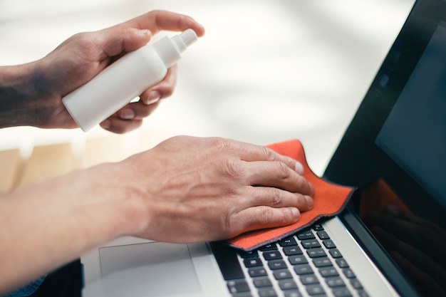 Zdjęcie Ścieśniać. człowiek rozpylanie sprayu na powierzchni laptopa. koncepcja ochrony zdrowia