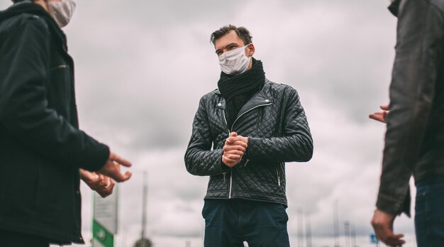 Ścieśniać. młodzi ludzie w maskach ochronnych rozmawiają stojąc w bezpiecznej odległości