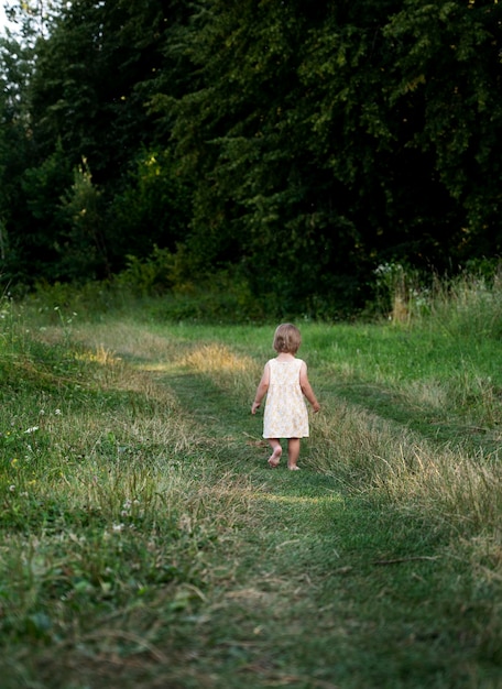 Ścieżką biegnie mała dziewczynka w letniej sukience