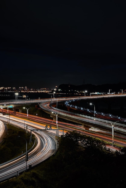 Ścieżki światła na drodze w mieście na tle nocnego nieba
