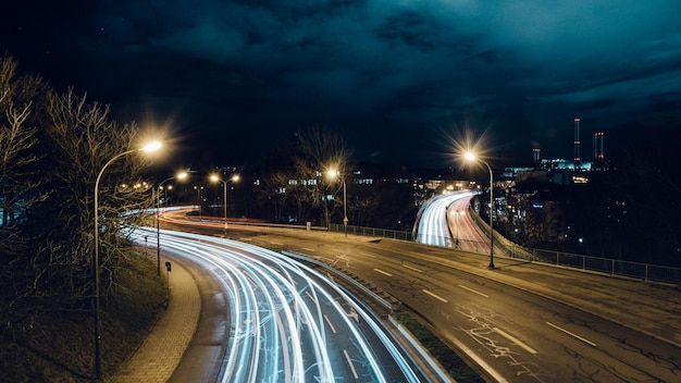 Ścieżki światła na drodze w mieście na tle nocnego nieba