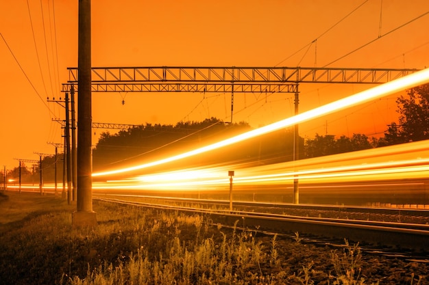 Zdjęcie Ścieżki światła na torach kolejowych na pomarańczowym niebie podczas zachodu słońca