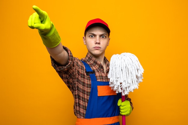 Zdjęcie Ścisłe punkty z przodu młody sprzątacz ubrany w mundur i czapkę z rękawiczkami, trzymający mop