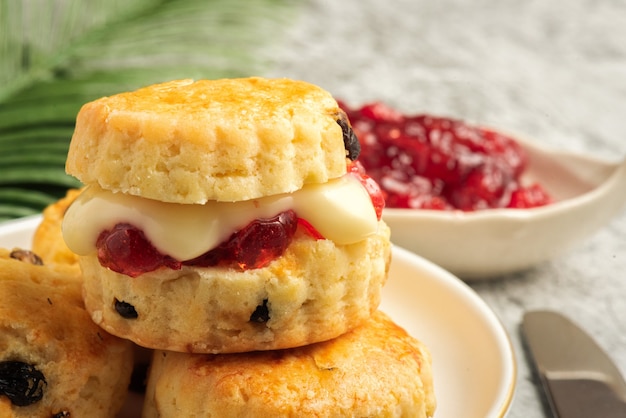 Scone w białym talerzu i dżemie truskawkowym na tle cementu