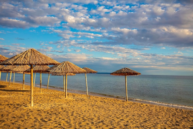 Seascape z słomianymi parasolami na piaszczystej plaży Bezludna plaża o zachodzie słońca