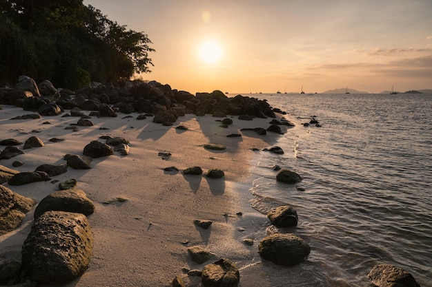 Seascape ze skałami na linii brzegowej w tropikalnym morzu na zachodzie słońca