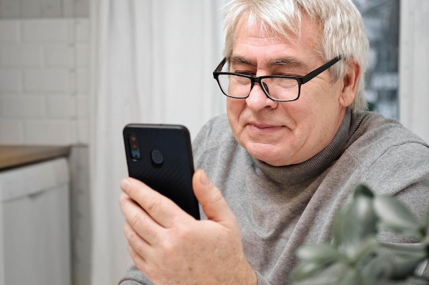 Sędziwy starzec patrzący na kamerę internetową trzymający telefon rozmawiający z żoną dzieci online Starszy dziadek uśmiechający się na czacie z rodziną przyjaciół przez rozmowę wideo Nowoczesne technologie i starsza generacja
