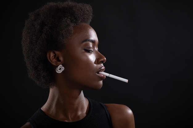 Seksowna afroamerykanka paląca papierosa na czarnym tle