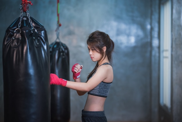 Seksowna Asia dziewczyna uderza pięścią bokserską torbę