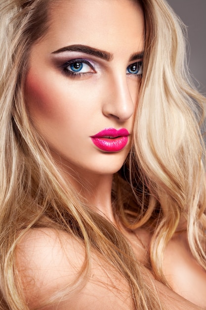Seksowna blondynka z makijażem i niebieskimi oczami patrząc z przodu