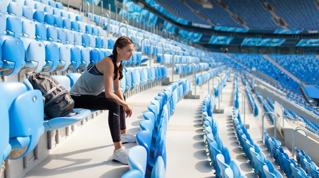 Seksowna dziewczyna pozuje przy stadium.