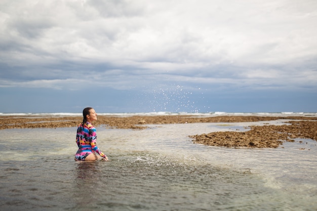 Seksowna kobieta pozuje przy ocean plażą.