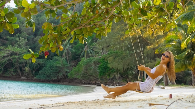 Seksowna kobieta spędza wakacje nad morzem Dziewczyna huśta się na huśtawce Koncepcja wesołych świąt radość lekkość świeże powietrze czystość i zdrowie