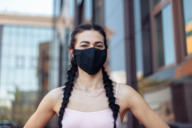 Seksowna kobieta w czarnej masce w mieście ćwiczy podczas pandemii COVID-19 lub zanieczyszczenia powietrza