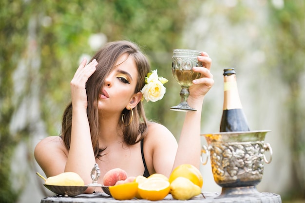 Seksowna kobieta ze świeżymi owocami na stole w parku na świeżym powietrzu Zmysłowa młoda kobieta pije szampana